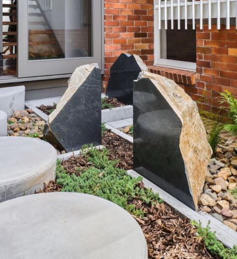 large uniform concrete discs make a path next to a boulder that has been cut and the inside polished