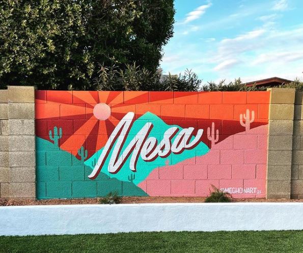 29 Unique Garden Mural Ideas for Outdoor Walls & Fences 11 a garden wall with a bright mural in warm colours that says "Mesa" in the middle