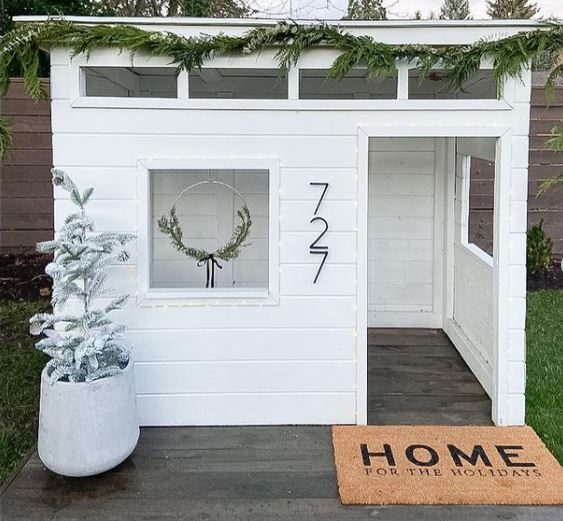 a white, mid-century style playhouse with wood floors and no front door
