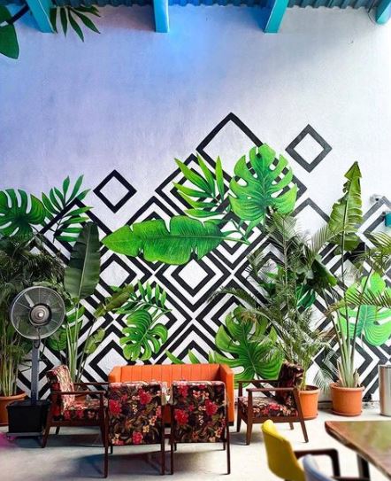 29 Unique Garden Mural Ideas for Outdoor Walls & Fences 8 a seating area with a large mural of geometric shapes and lifelike plant leaves
