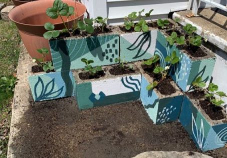 The Secret to a Manicured Landscape: 16 Garden Lawn Edging Ideas 7 stacked up concrete breezeblocks being used as planters, all painted in various patterns and shades of blue