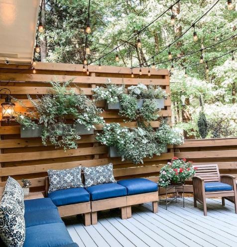a garden deck area with taller fencing made from pallets behind the seating