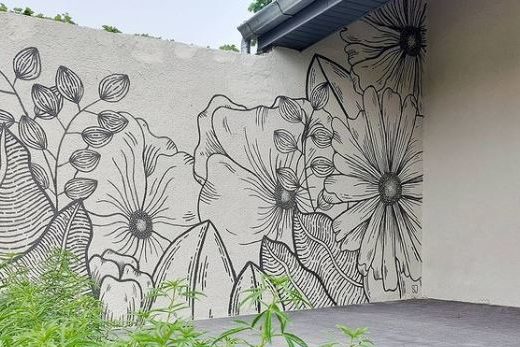 a black line drawing of flowers and leaves on a white garden wall