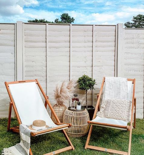 garden fencing ideas for painting: two deckchairs on an artificial lawn in front of a clean fence painted light grey