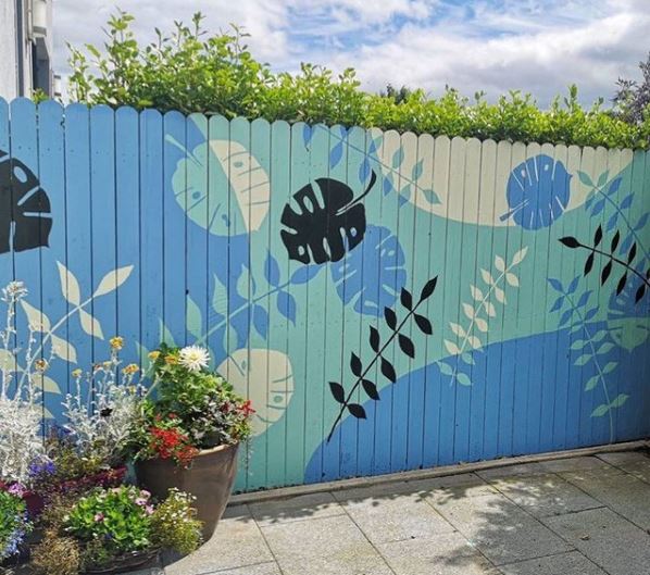 29 Unique Garden Mural Ideas for Outdoor Walls & Fences 6 a garden fence painted with tropical leaf prints in shades of blue and turquoise