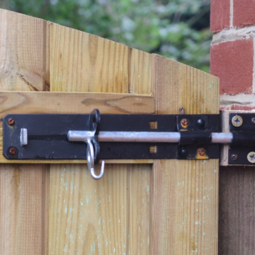 a long metal bolt securing a wooden gate into a brick wall