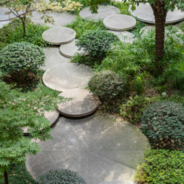 round concrete stepping stones overlapping through circular shrubs and flower beds