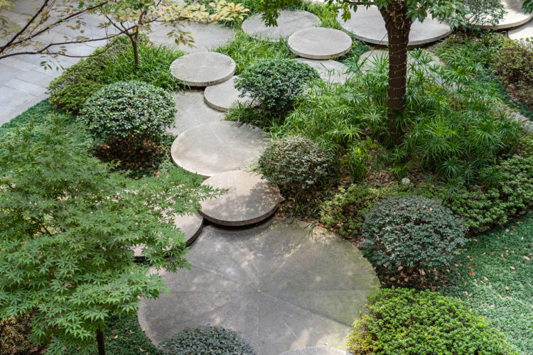 round concrete stepping stones overlapping through circular shrubs and flower beds