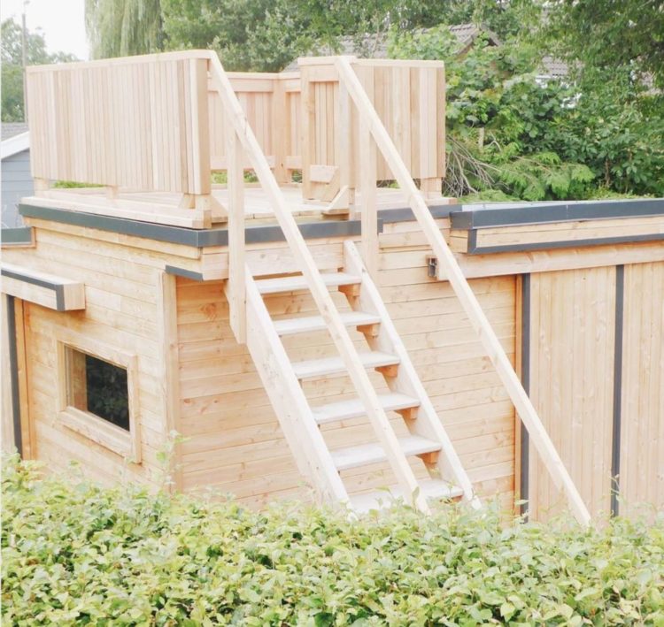11 Awesome Garden Treehouse Ideas for You (and Your Kids) 5 a wooden shed with a ladder up to a rooftop platform