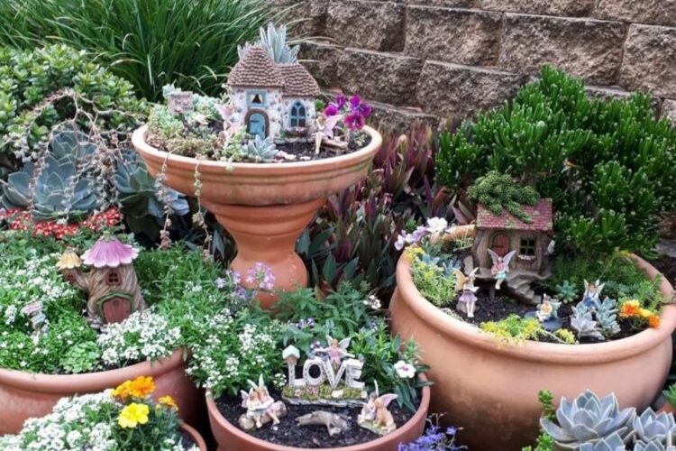 a garden with lots of pots, some of which have little fairy houses and decorations in