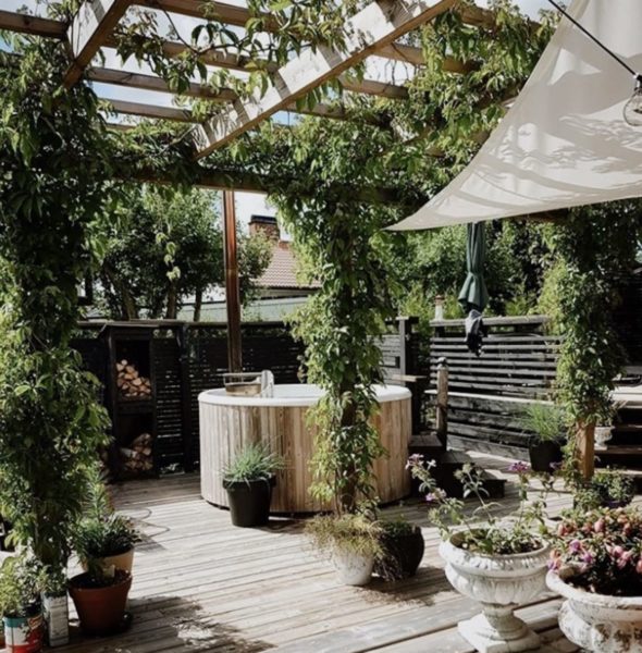 18 Garden Gazebo Ideas for an Outdoor Shelter from the Sun 24 a pergola covering a deck with a hot tub in the middle, completely surrounded by plants in pots and planters, growing over the shelter
