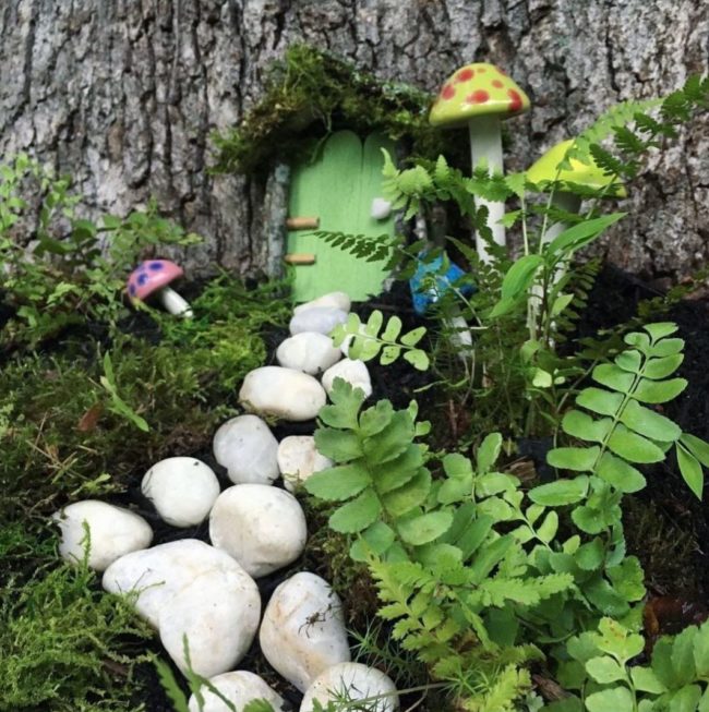 fairy garden ideas using white pebbles as a path to a miniature door