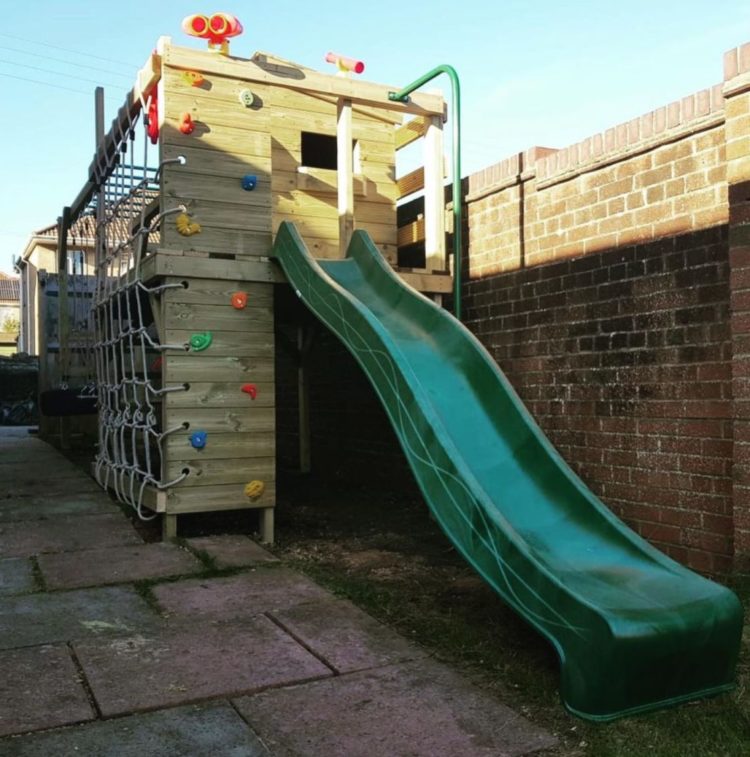 11 Awesome Garden Treehouse Ideas for You (and Your Kids) 7 a raised playhouse with a climbing wall and a slide