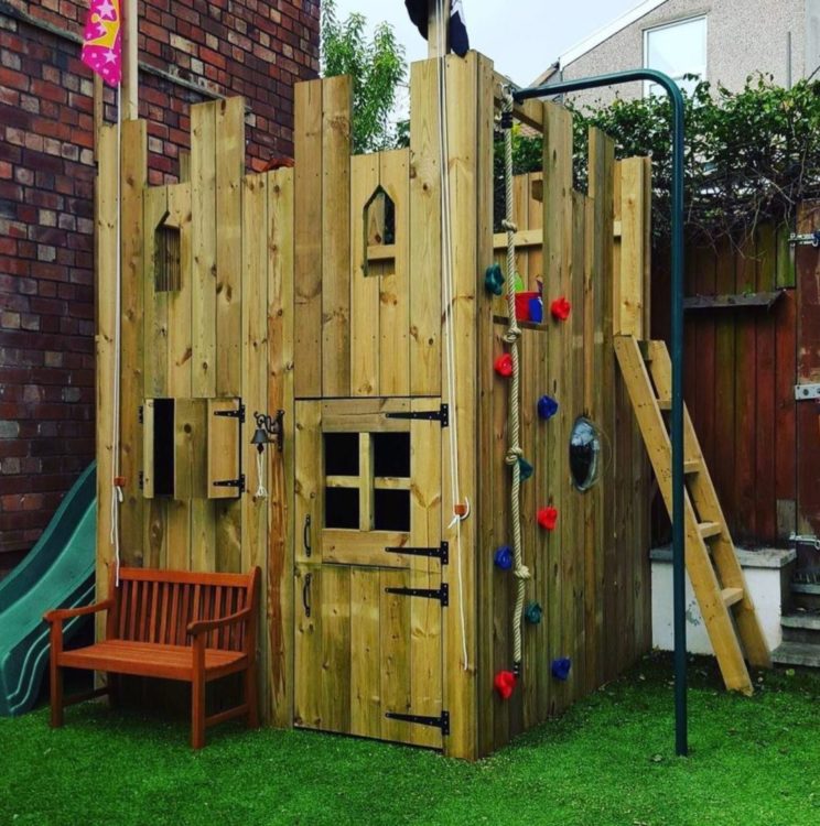 11 Awesome Garden Treehouse Ideas for You (and Your Kids) 13 a small wooden playhouse with a ladder, climbing wall and slide