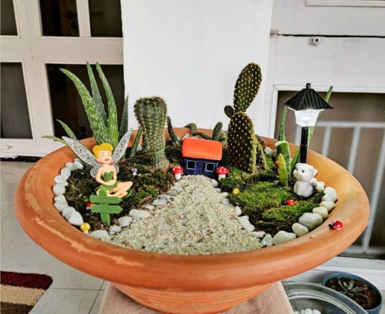 a wide terracotta pot with gravel, cacti and tiny, fairy-sized figurines