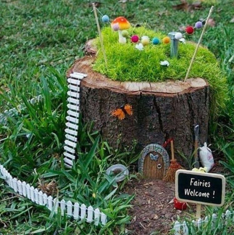 a tree stump decorated with tiny, fairy garden features