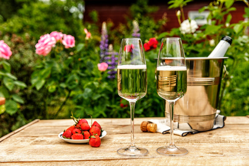 two glasses of champagne on a table next to a champagne bucket and plate of strawberries