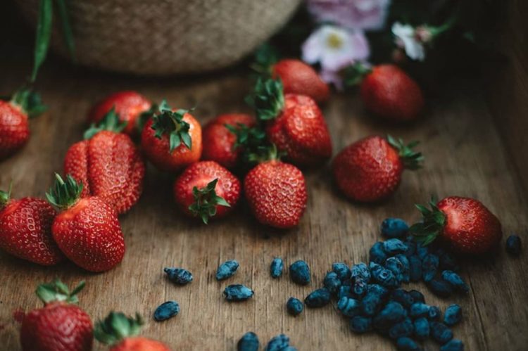 an artistic close up of fresh strawberries on a wooden surface