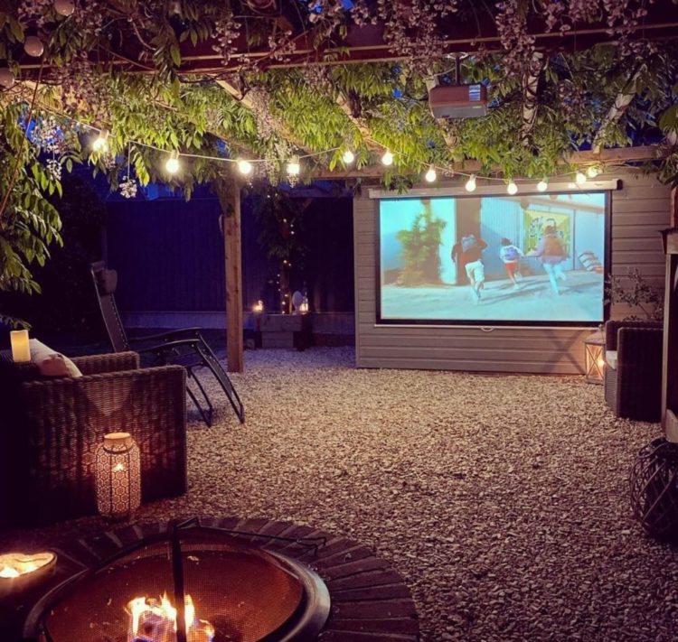 Wisteria Hysteria: Growing an Instagram-Worthy Garden 20 a gravelled garden with chairs under a wisteria covered pergola, facing a projector screen