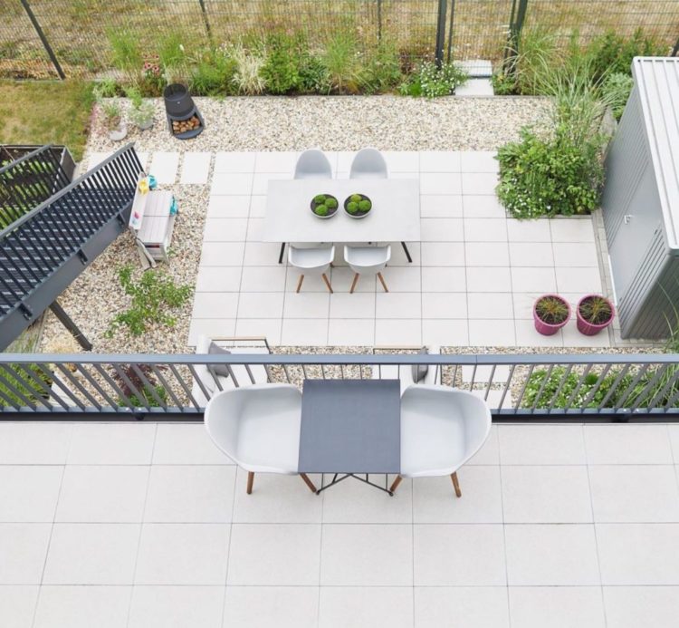 a top-down view of a balcony overlooking a patio, both with cream paving stones