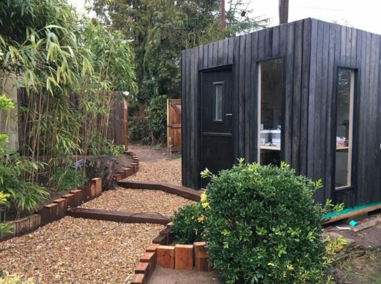 a small black garden office with black wood cladding
