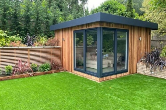 a modern, cube-shaped garden office in the corner of a garden