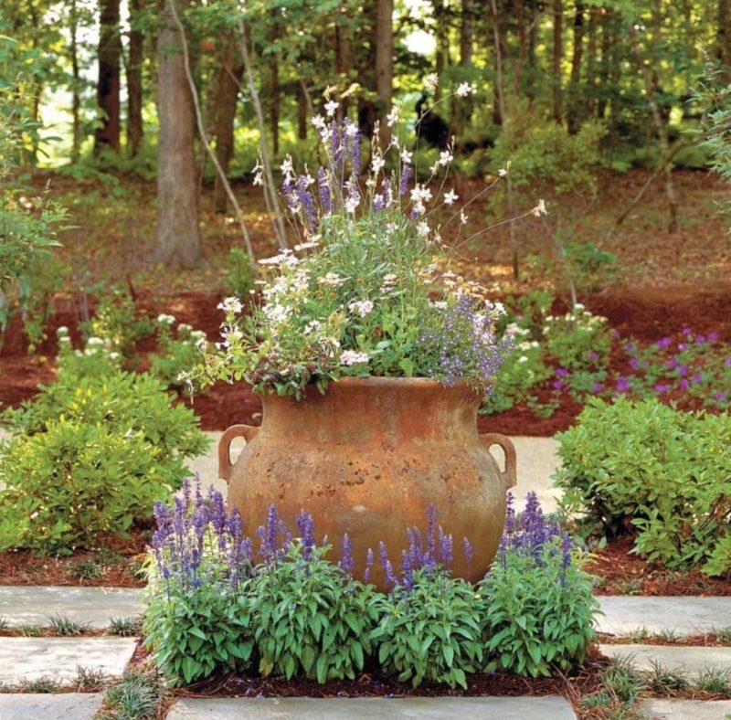 a stone urn with flowers growing around the sides and out the top