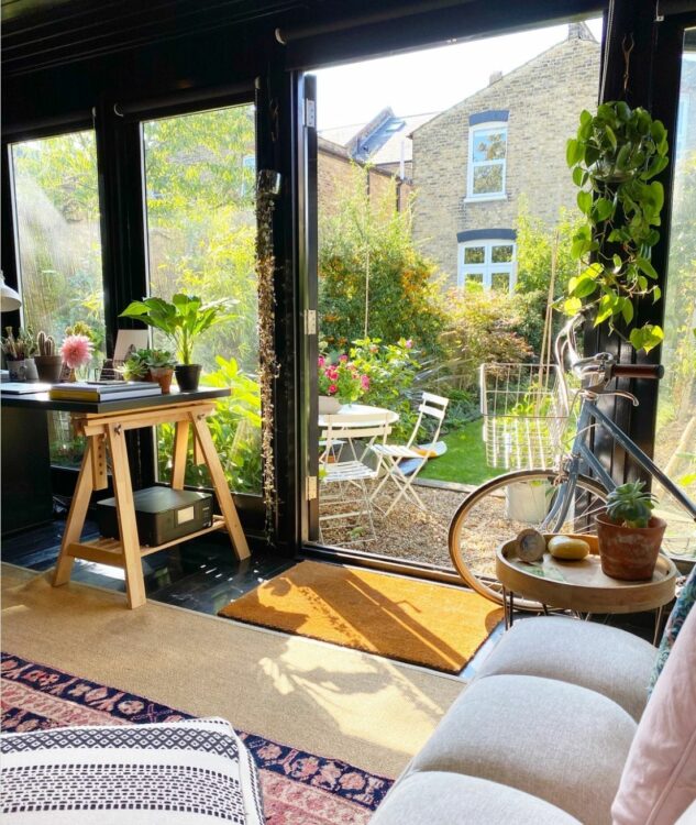 interior view of a garden office looking out - there's a sofa and desk visible