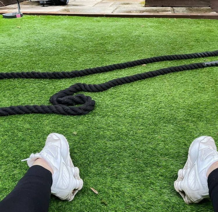 battle ropes, or exercise ropes, are strewn across a lawn made from artificial turf