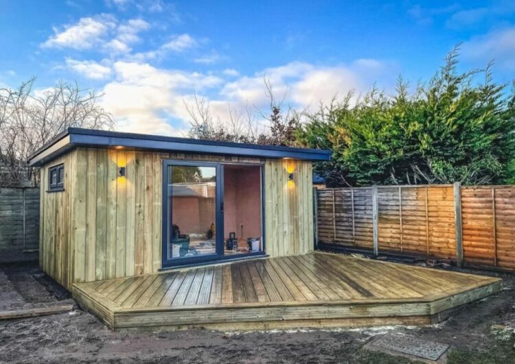a wooden garden office with a large deck attached to the front