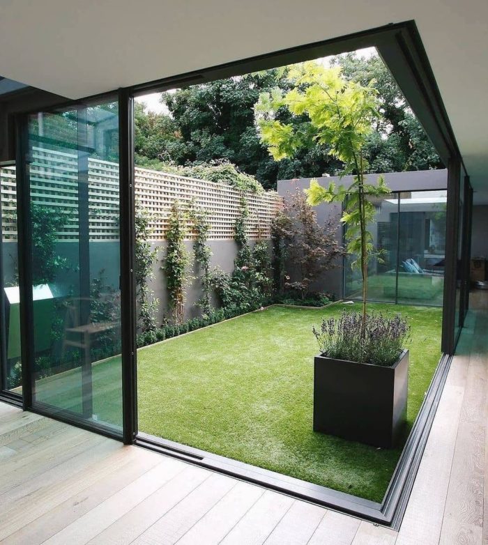 a minimalist courtyard with an artificial lawn is surrounded on three sides