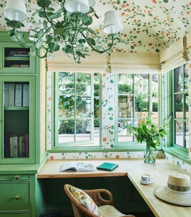 garden office interior with green woodwork, leaf-print wallpaper and floral light fitting