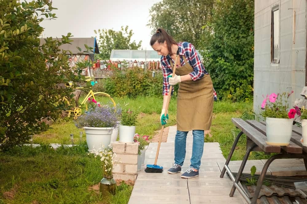 woman gardener sweeping the garden